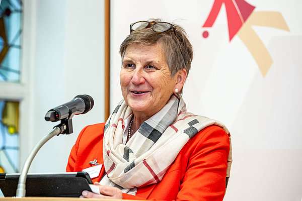 Alternativ Text (Alt-Tag)
- Dr. Claudia Lücking-Michel begrüßt Nominierte, Gäste und Mitarbeiter*innen von AGIAMONDO.